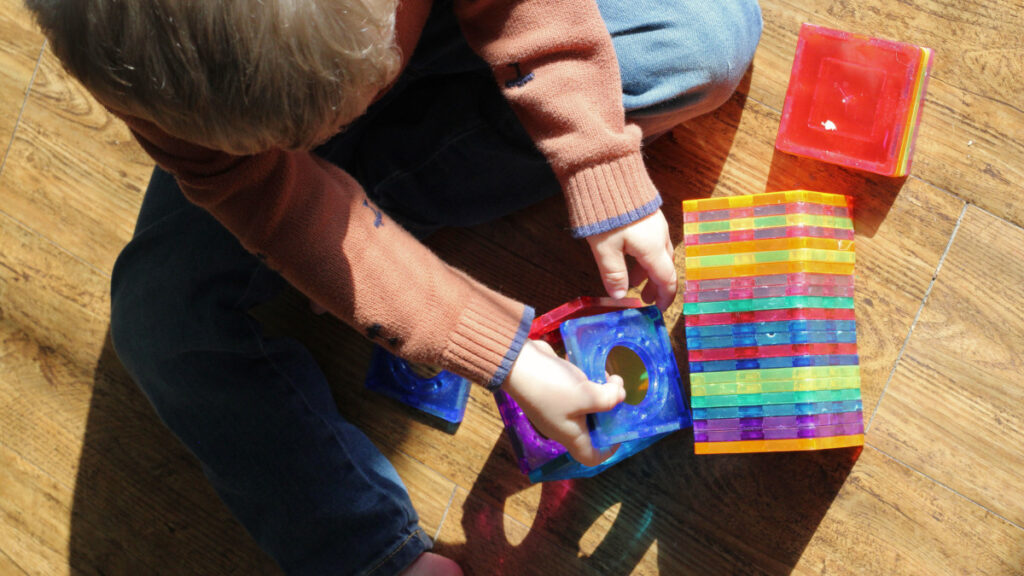 little boy playing with magnet tiles on the floor