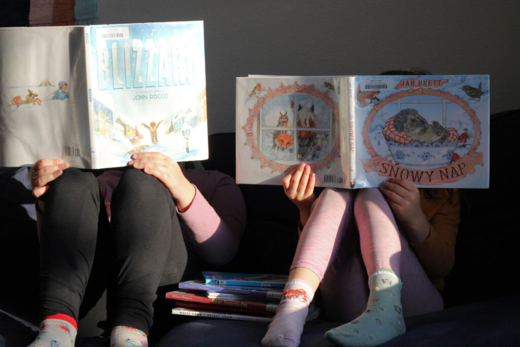 two children holding and reading picture books